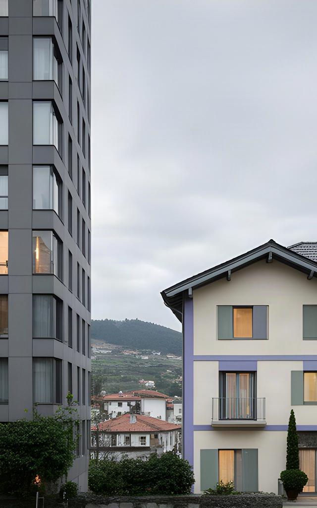 Fachada de un edificio corporativo junto a una vivienda familiar en Asturias